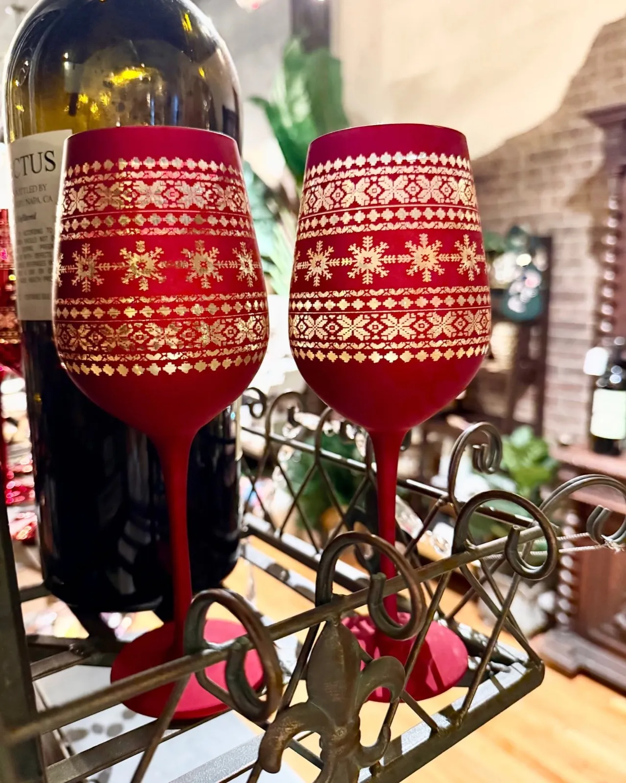 Two deep red stemmed wine glasses with a band of gold snowflakes