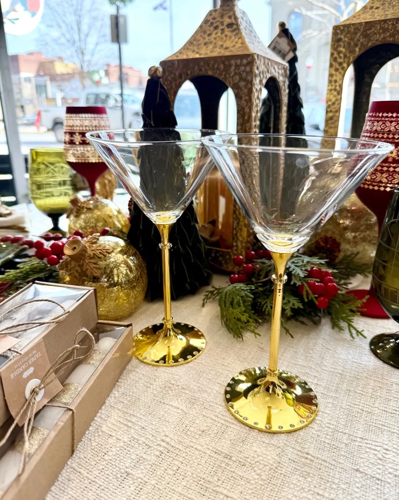 Two martini glasses with gold stems on a linen-covered table in the shop window