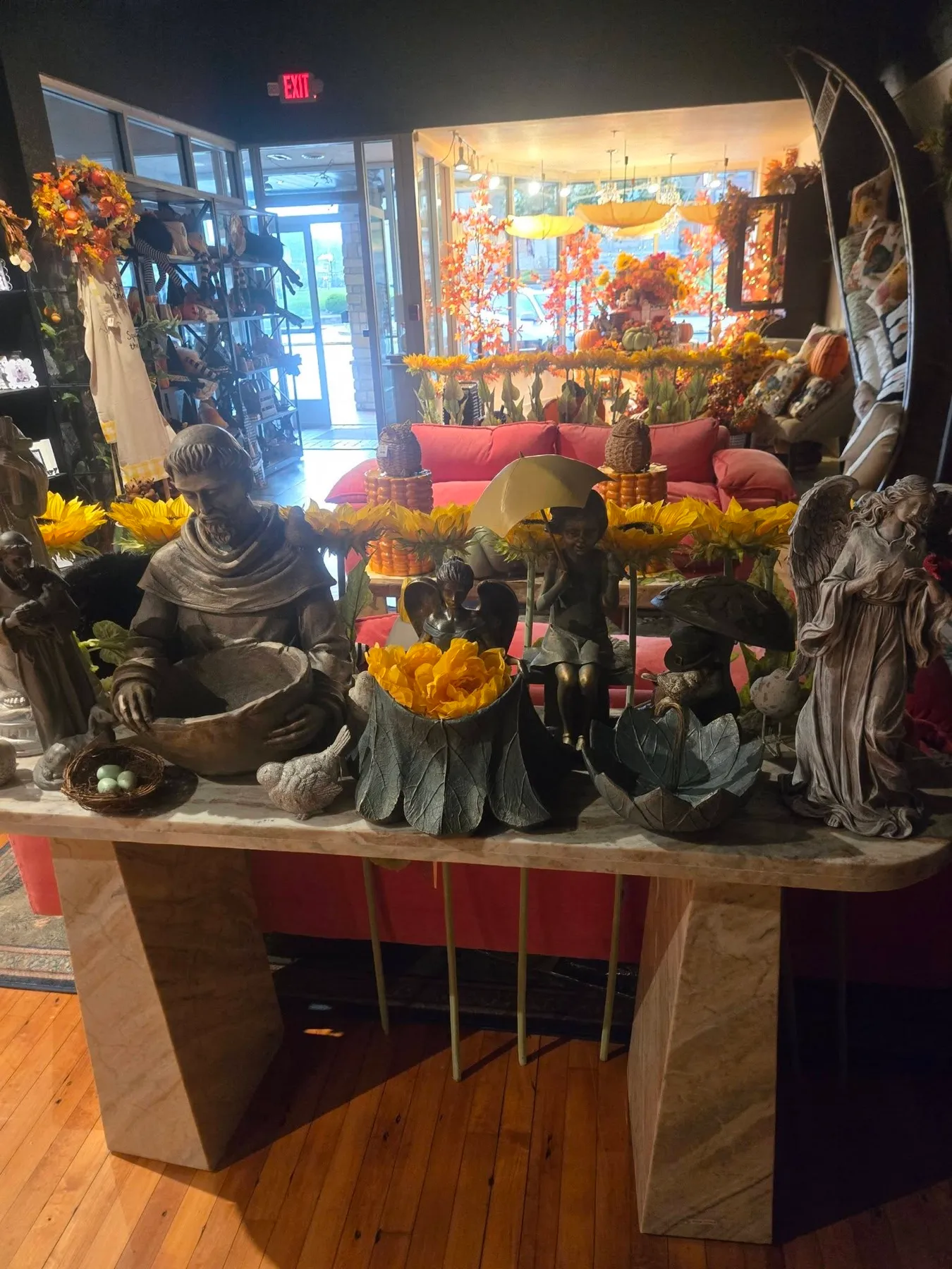Garden statuary and planters on a marble table, the front window glowing behind